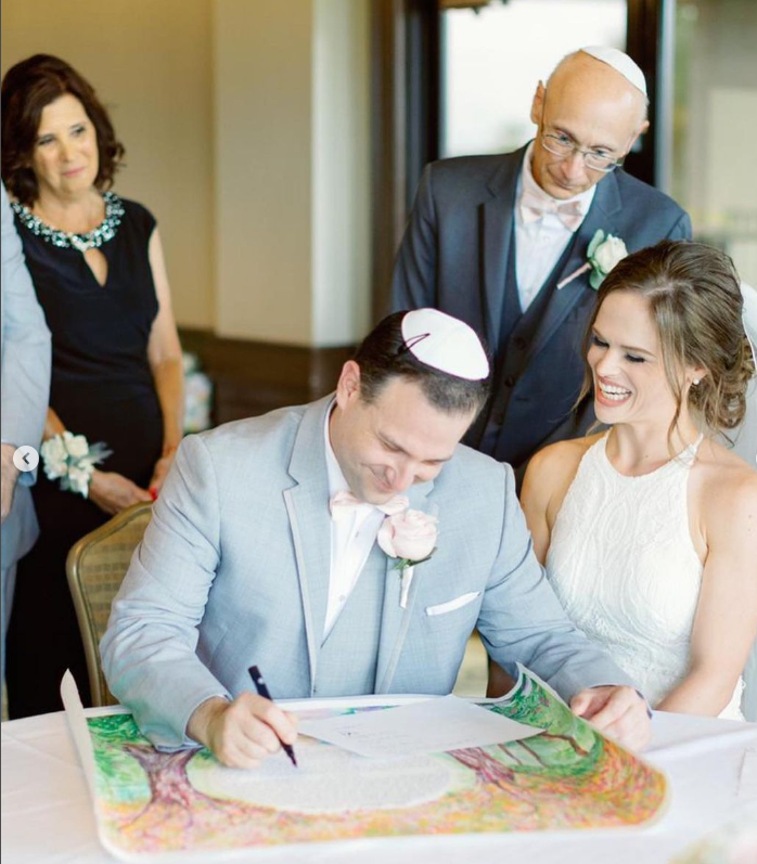 Couple signing their custom made ketubah - Avigail Sapir Art
